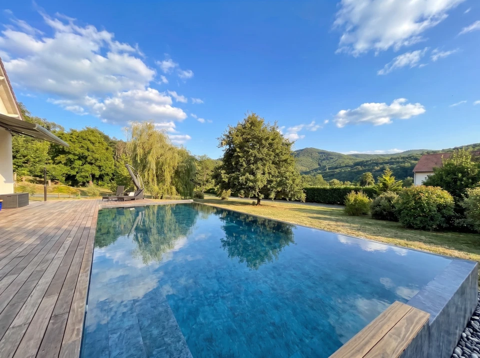 Espace spa intérieur luxueux de nuit, avec piscine rectangulaire et jacuzzi circulaire attenant illuminés en bleu électrique